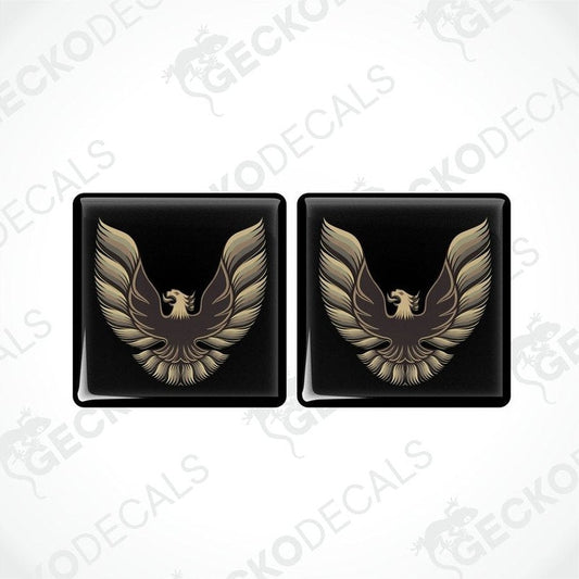 Two black vinyl stickers with a gold and bronze emblem design, placed against a white background.