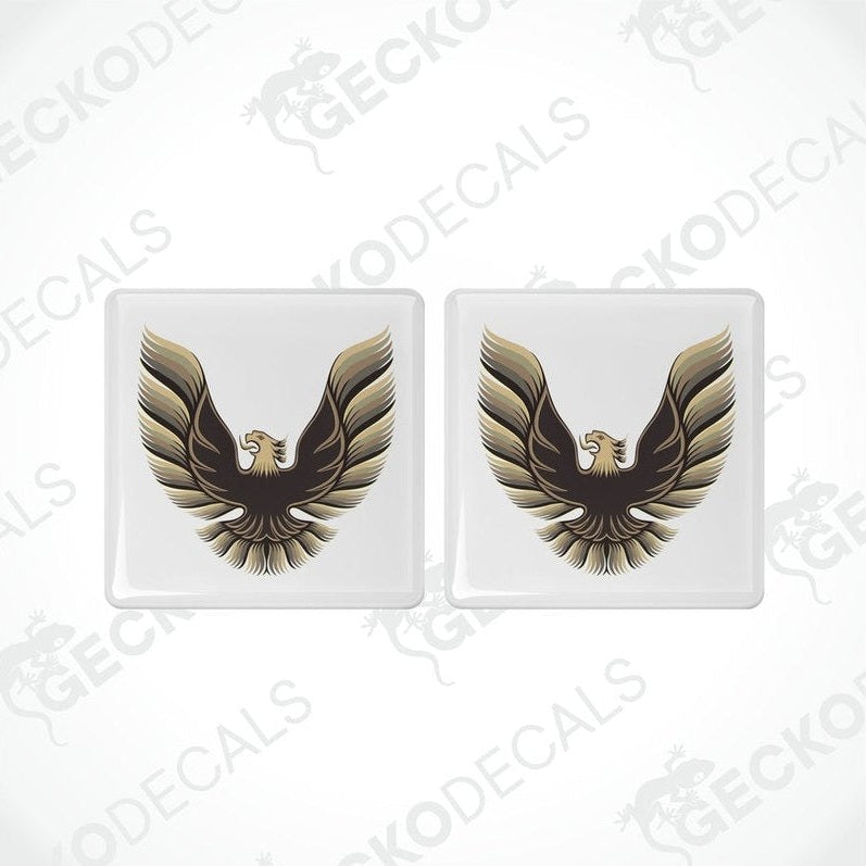 Two withe vinyl stickers with a gold and bronze emblem design, placed against a white background.