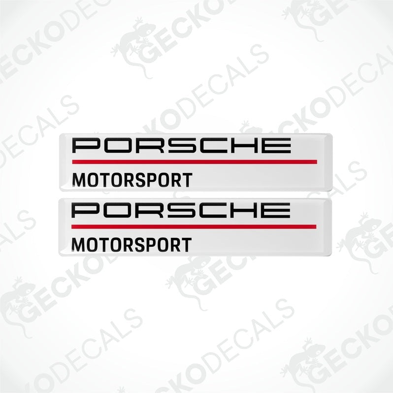 Two rectangular withe vinyl decals with 'PORSCHE MOTORSPORT' text in black and red.