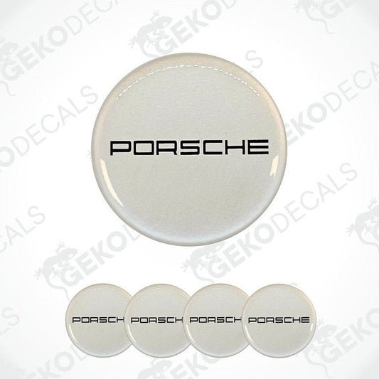 A set of four white vinyl stickers with the PORSCHE logo on them. The stickers are designed to be used on car wheel caps.