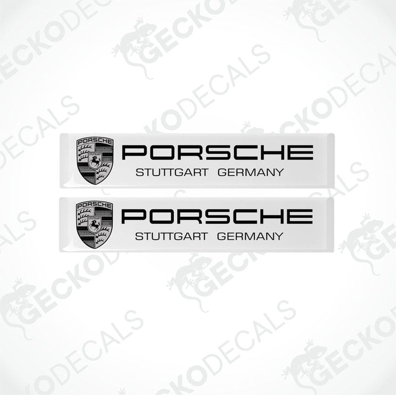Two withe rectangular vinyl decals with the text 'PORSCHE STUTTGART GERMANY' on them, placed on a black background.