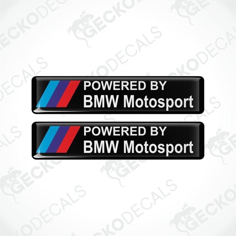 Two black vinyl stickers with the text 'POWERED BY BMW MOTOSPORT' and the BMW logo in red, white, and purple.