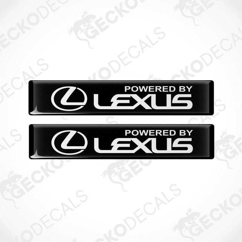Two black rectangular car decals with the white text 'POWERED BY LEXUS' on the front.
