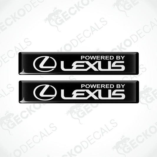 Two black rectangular car decals with the white text 'POWERED BY LEXUS' on the front.