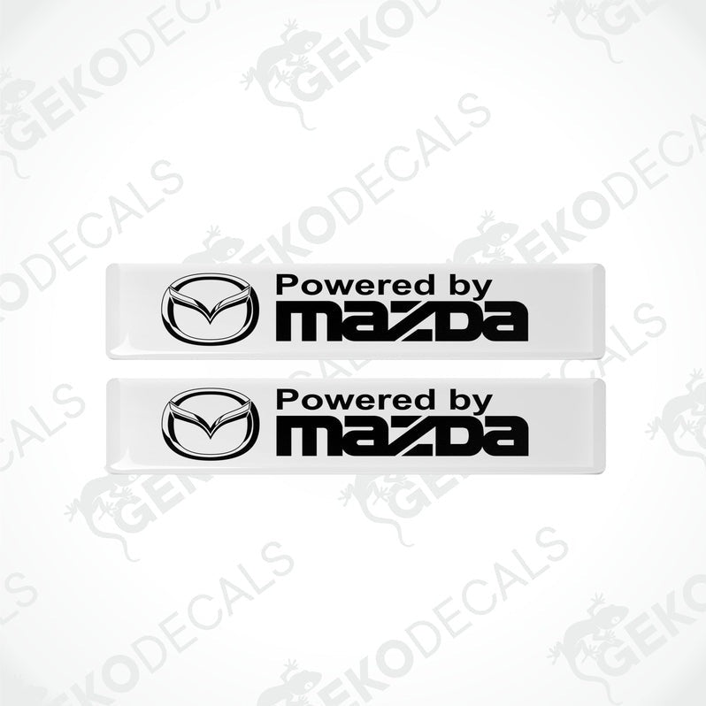 Two white vinyl stickers with the Powered by MAZDA logo in black.