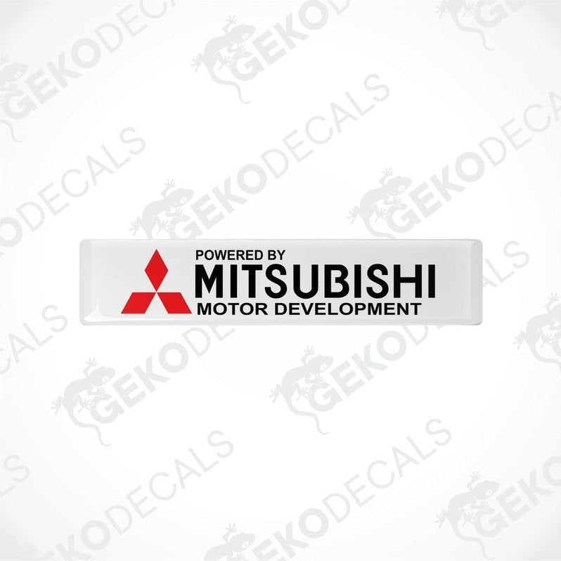 Rectangular white vinyl decals with the red Mitsubishi logo and the text 'POWERED BY MITSUBISHI MOTOR DEVELOPMENT'.