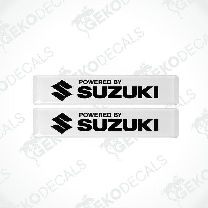Two withe vinyl stickers with the text 'POWERED BY SUZUKI' and the Suzuki logo.