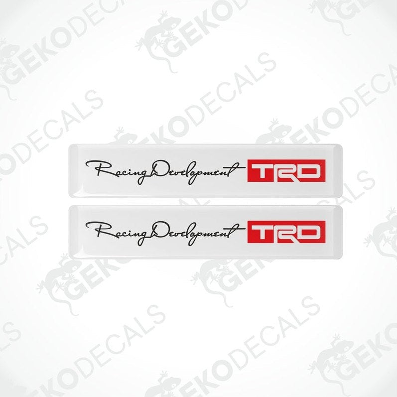Two withe vinyl decals with black and red text and logos, one decal reads 'Racing Development' and the other has 'TRD' logo.