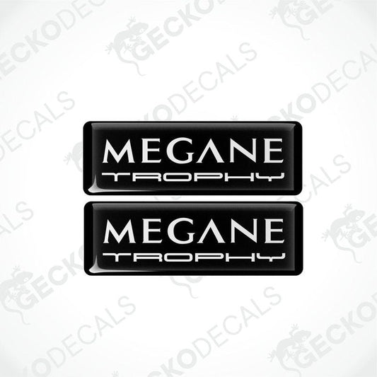 Two black rectangular vinyl decals with 'MEGANE TROPHY' white text on them, intended for use as car stickers.