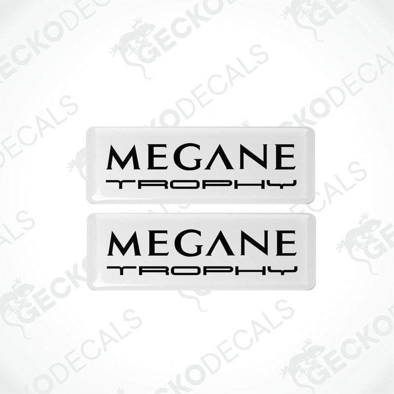 Two withe rectangular vinyl decals with 'MEGANE TROPHY'black text on them, intended for use as car stickers.