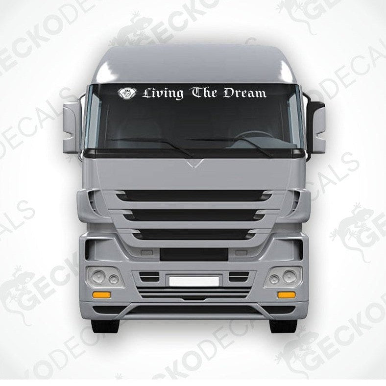 A die cut sticker with the phrase 'Living The Dream' applied to the front windscreen of a gray truck.