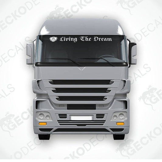 A die cut sticker with the phrase 'Living The Dream' applied to the front windscreen of a gray truck.