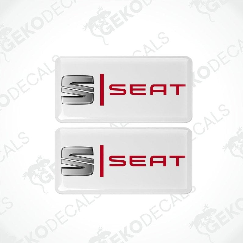 Two withe vinyl stickers with the word 'SEAT' in red and silver.