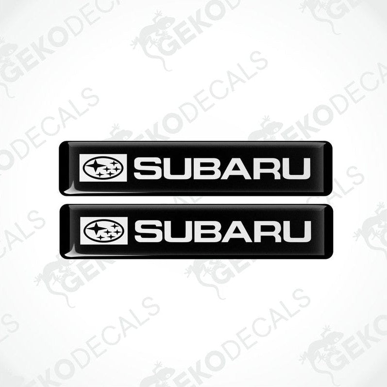 Two black decals with the Subaru car logo and the word 'SUBARU' in white letters.