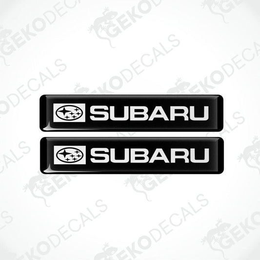 Two black decals with the Subaru car logo and the word 'SUBARU' in white letters.
