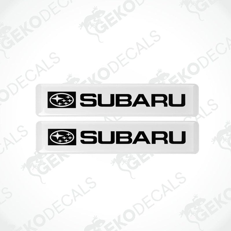 Two withe decals with the Subaru car logo and the word 'SUBARU' in white letters.