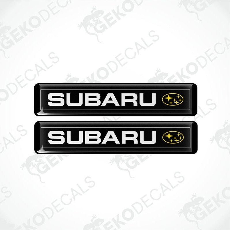 Two black vinyl decals with the Subaru brand logo in white and yellow.
