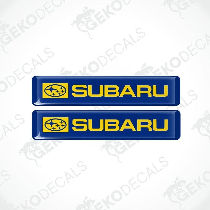 Two blue decals with the Subaru car logo and the word 'SUBARU' in yellow letters.
