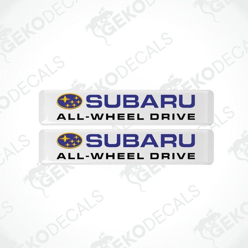 Two white vinyl stickers with the Subaru brand logo and the slogan 'ALL-WHEEL DRIVE' printed in blue and yellow.