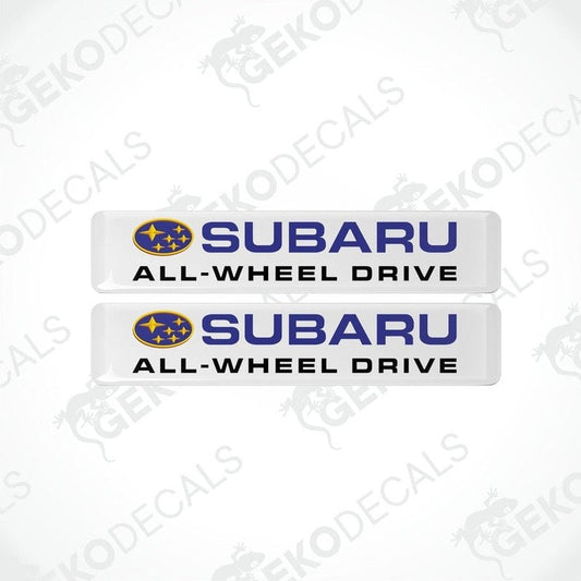 Two white vinyl stickers with the Subaru brand logo and the slogan 'ALL-WHEEL DRIVE' printed in blue and yellow.