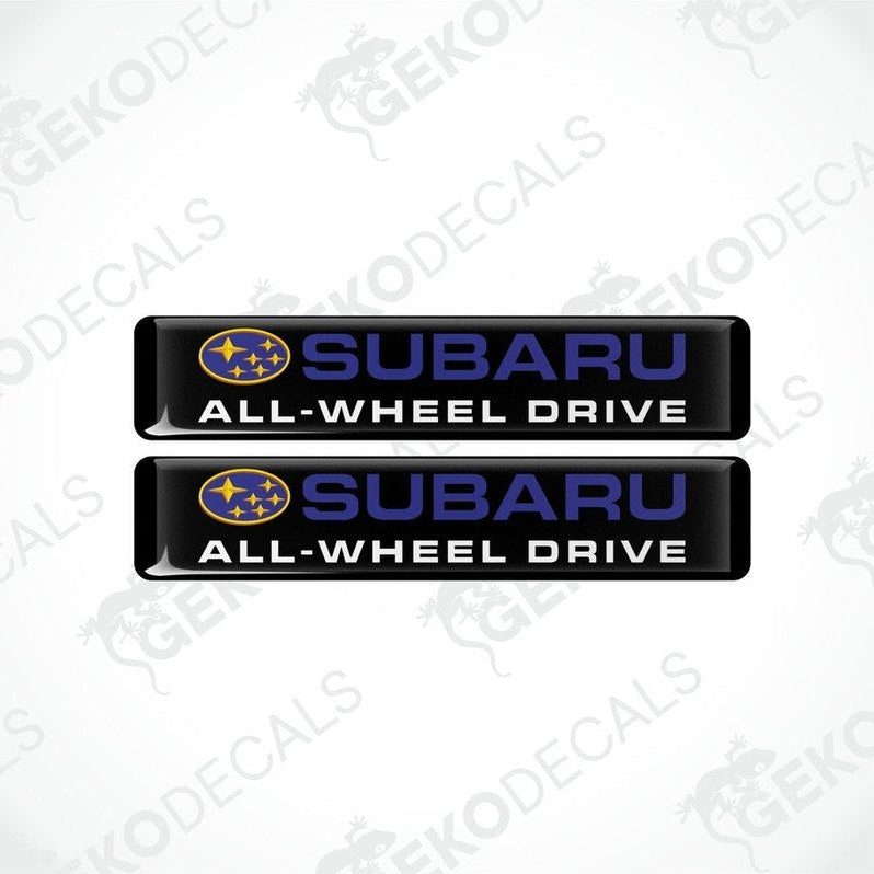 Two black vinyl stickers with the Subaru brand logo and the slogan 'ALL-WHEEL DRIVE' printed in blue and yellow.