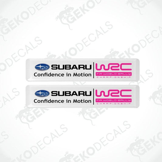 Two rectangular vinyl decals with a polyurethane coating featuring the Subaru logo and 'Confidence in Motion' slogan in pink and white colors.