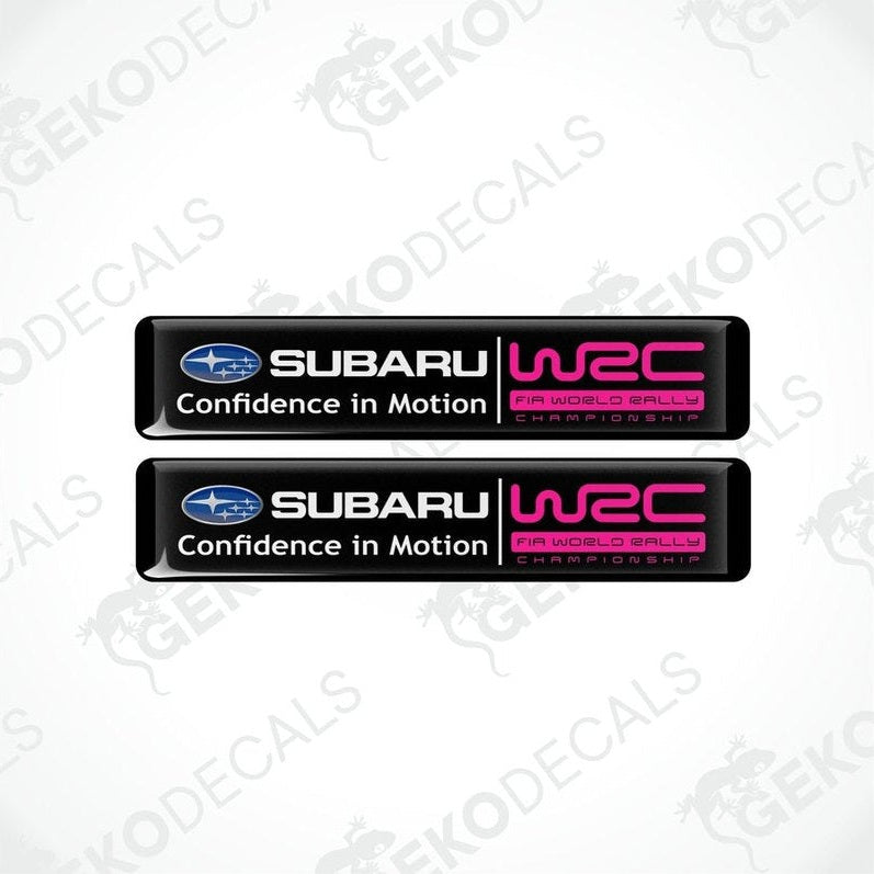 Two rectangular vinyl decals with a polyurethane coating featuring the Subaru logo and 'Confidence in Motion' slogan in pink and black colors.