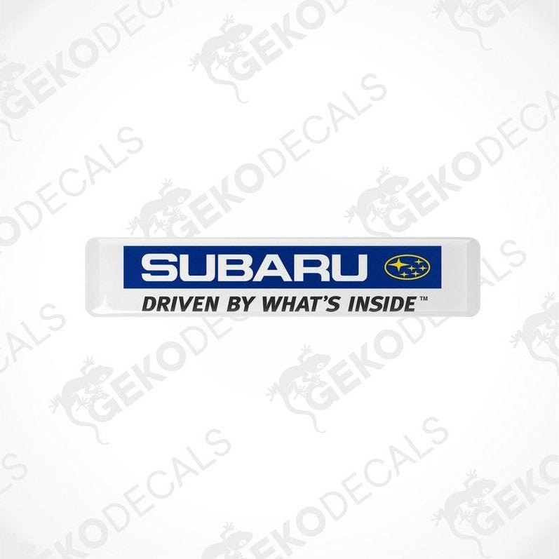  White vinyl stickers with the Subaru brand logo and the slogan 'DRIVEN BY WHAT'S INSIDE' printed in blue and yellow.