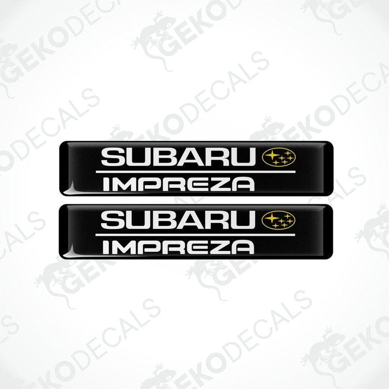 Two black decals with the Subaru car logo and the word 'SUBARU IMPREZA' in yellow letters.