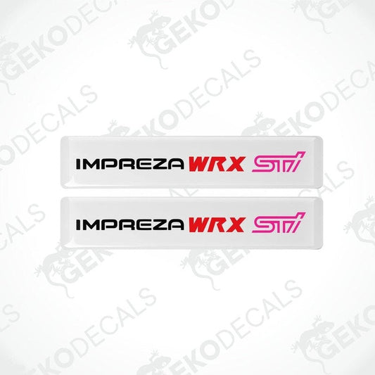 Two white vinyl stickers with the text 'IMPREZA WRX STI' in red and pink. The stickers are designed to be applied on a vehicle.