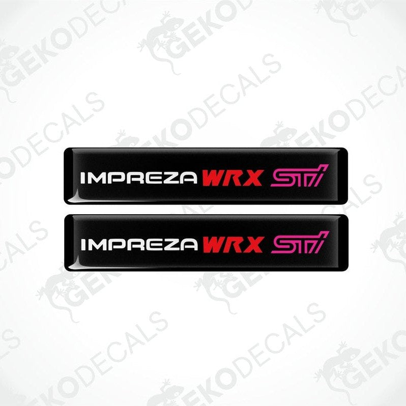 Two black vinyl stickers with the text 'IMPREZA WRX STI' in red and pink. The stickers are designed to be applied on a vehicle.
