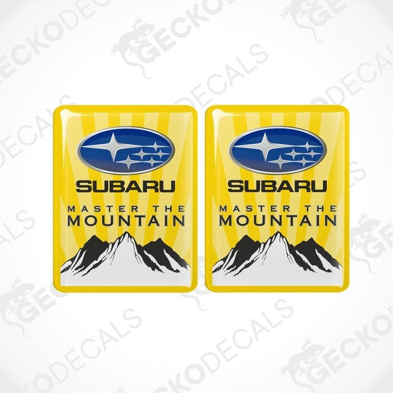 Two yellow vinyl stickers with the SUBARU brand logo and the text 'MASTER THE MOUNTAIN' along with a mountain range illustration.