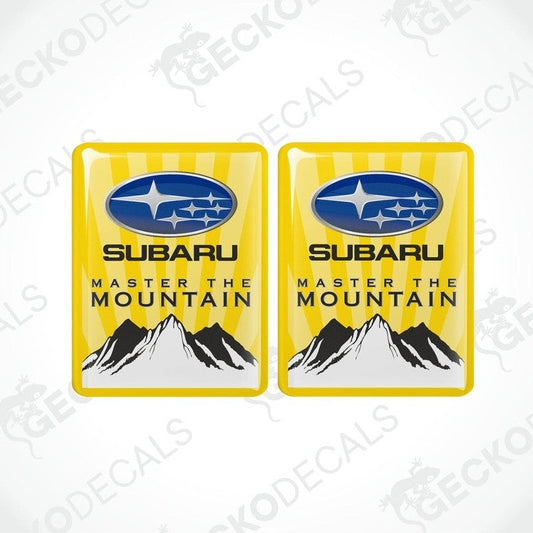 Two yellow vinyl stickers with the SUBARU brand logo and the text 'MASTER THE MOUNTAIN' along with a mountain range illustration.