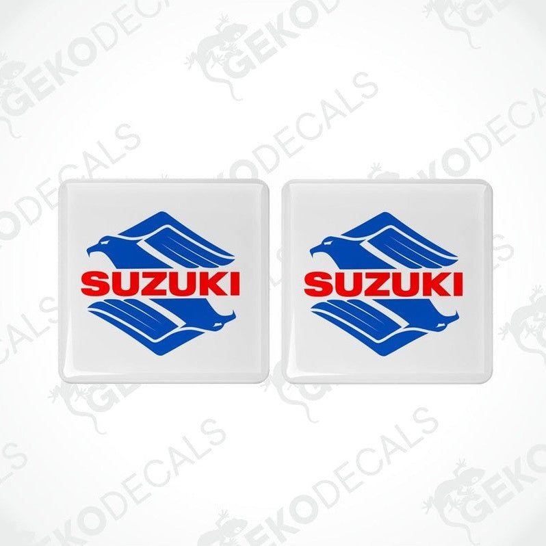 Two white square stickers with the SUZUKI brand logo in blue and red.