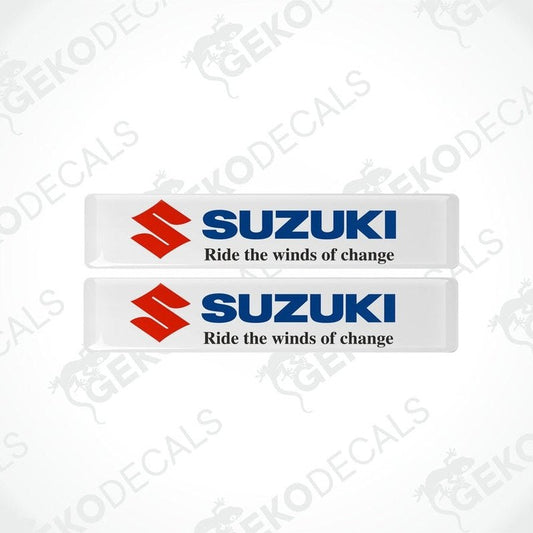 Two white rectangular vinyl decals with the SUZUKI logo and the phrase 'Ride the winds of change' printed on them.