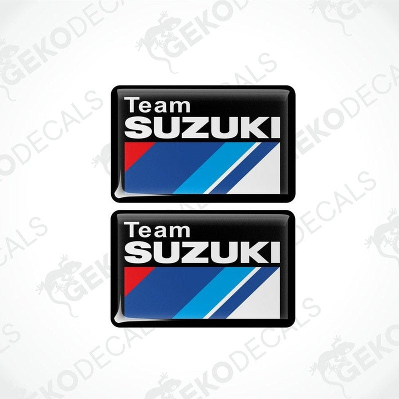 Two vinyl stickers with a TEAM SUZUKI design, featuring red, blue, white, and black colors and the Suzuki logo.