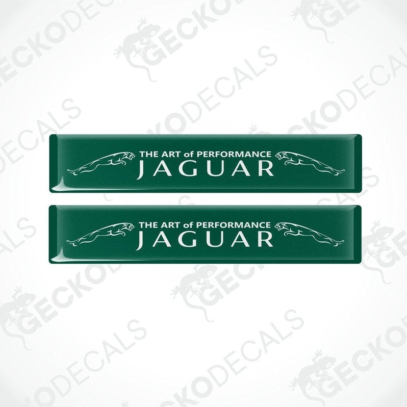 Two rectangular green car decals with white text that reads 'THE ART OF PERFORMANCE JAGUAR'.