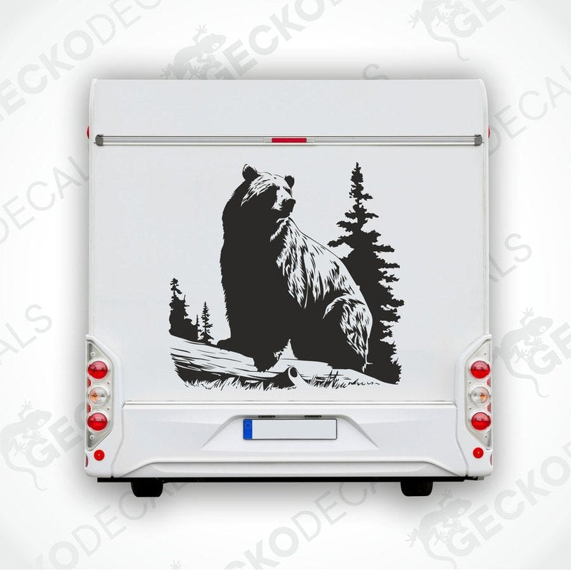 A die cut sticker of a black bear sitting on a stump with a forest backdrop, delivered on transfer paper.