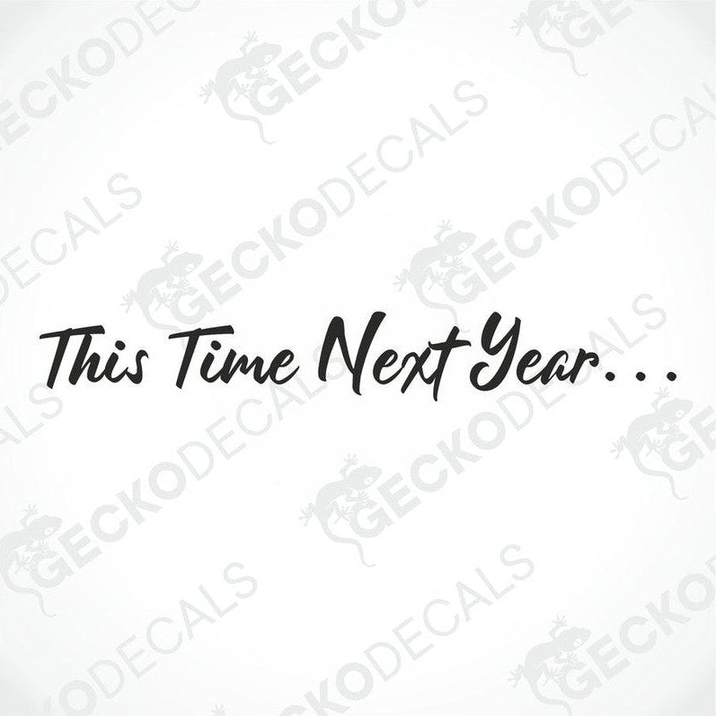A die cut decal with the phrase 'This Time Next Year...' displayed on the front windshield of a gray truck.