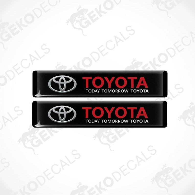 Two black vinyl stickers with the Toyota logo and the text 'TODAY TOMORROW TOYOTA' printed on them.