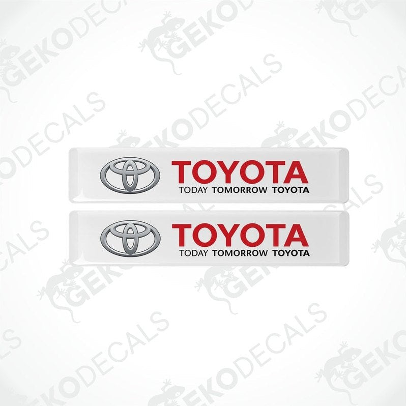 Two withe vinyl stickers with the Toyota logo and the text 'TODAY TOMORROW TOYOTA' printed on them.