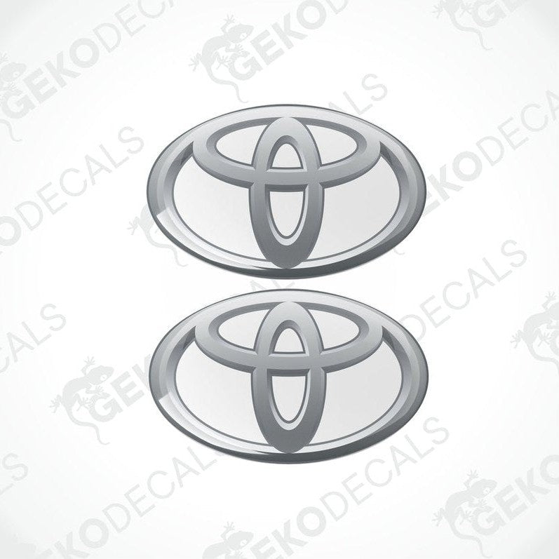 Two Toyota branded vinyl stickers with a dome shape and a silver and withe color scheme.