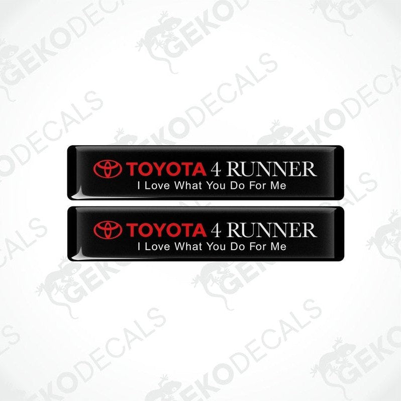 Two black rectangular car decals with white text, one saying 'TOYOTA 4 RUNNER' and the other with the phrase 'I Love What You Do For Me'.