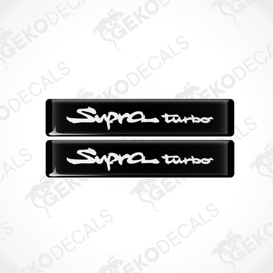 Two black vinyl decals with 'Supra turbo' text in white, indicating a set of car stickers for a Toyota Supra vehicle.