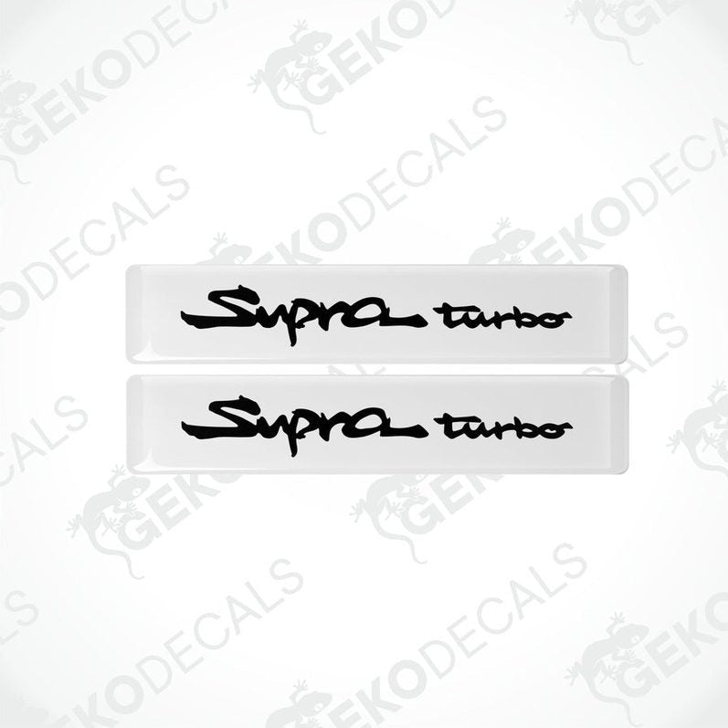 Two withe vinyl decals with 'Supra turbo' text in black, indicating a set of car stickers for a Toyota Supra vehicle.