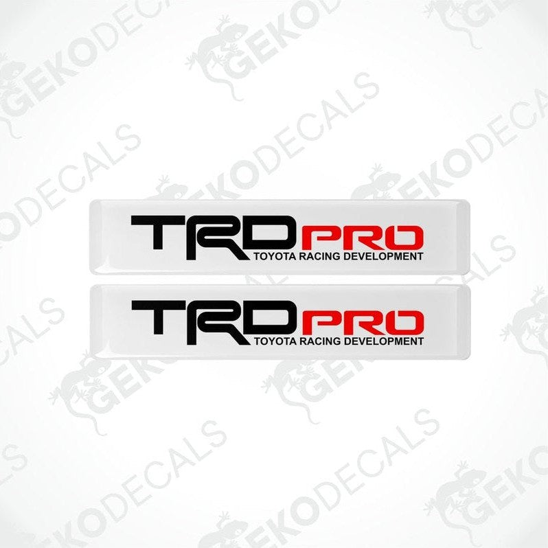 Two withe vinyl stickers with red and black text 'TRD PRO' and 'TOYOTA RACING DEVELOPMENT', placed on a white background.