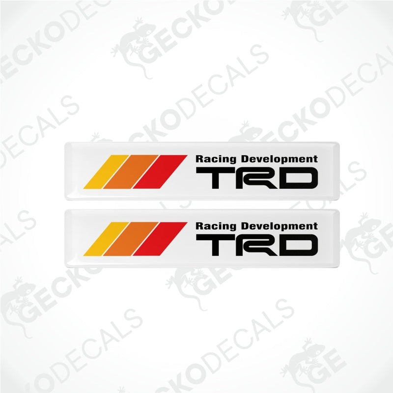Two TRD racing development decals with red and orange stripes on a white background.