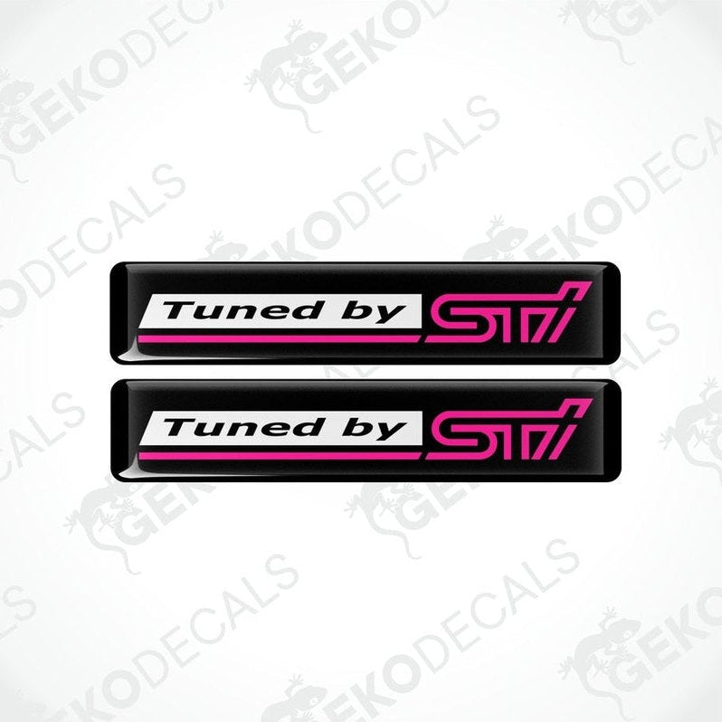 Two rectangular vinyl decals with a polyurethane coating, black with pink text, featuring the 'Tuned by STI' logo.