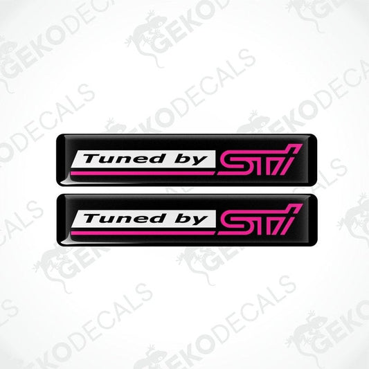 Two rectangular vinyl decals with a polyurethane coating, black with pink text, featuring the 'Tuned by STI' logo.
