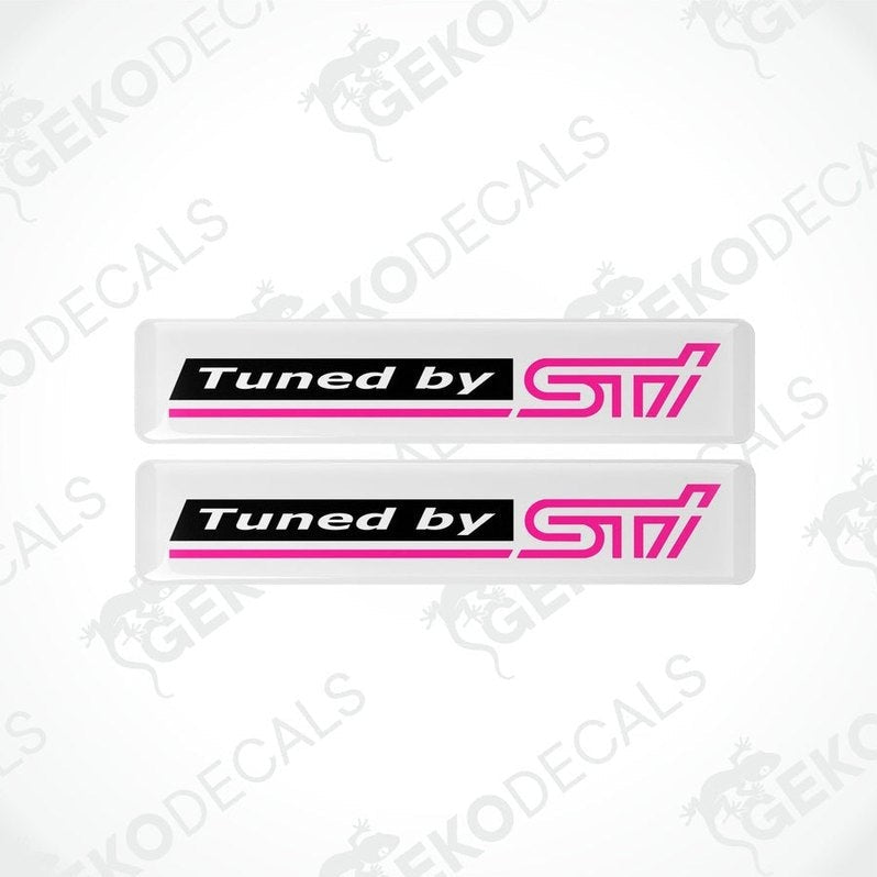 Two rectangular vinyl decals with a polyurethane coating, black with pink text, featuring the 'Tuned by STI' logo.